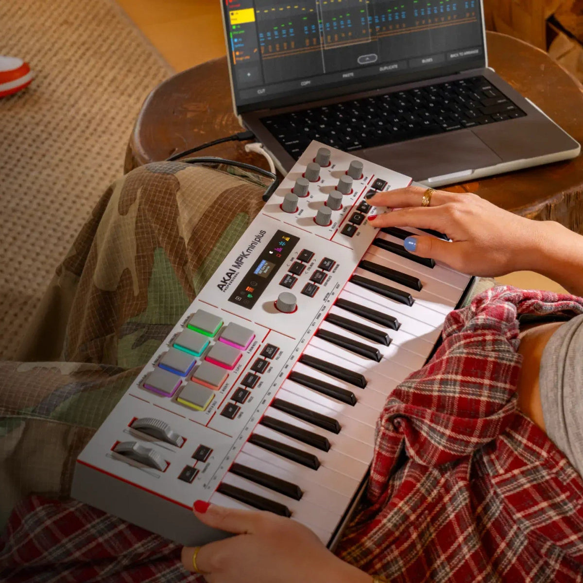Akai Professional MPK Mini Plus II played on the couch next to a laptop