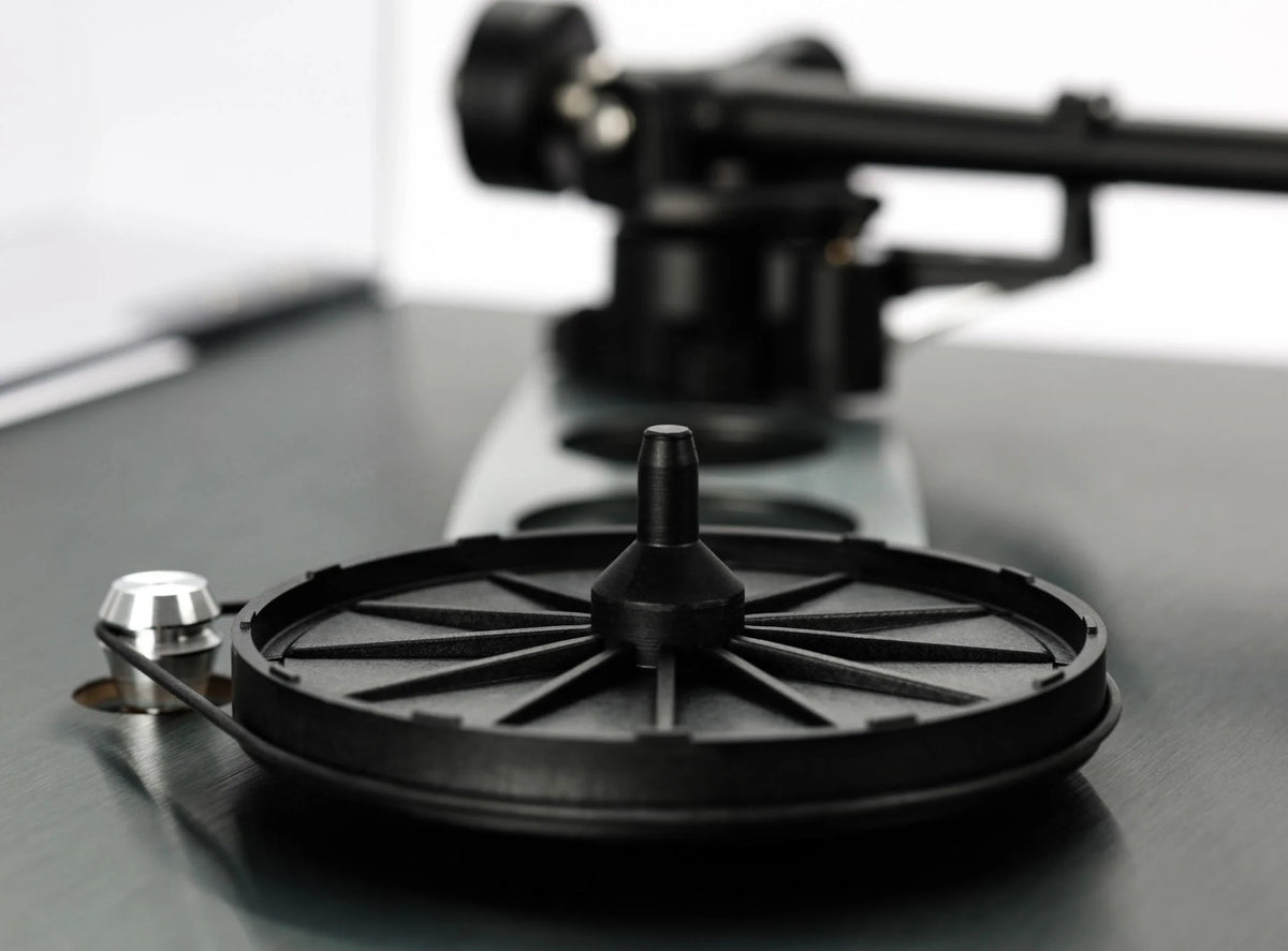 Close-up of Rega Planar 3 RS turntable with aluminum platter and Nd5 cartridge, showing the hub bearing and tonearm details.